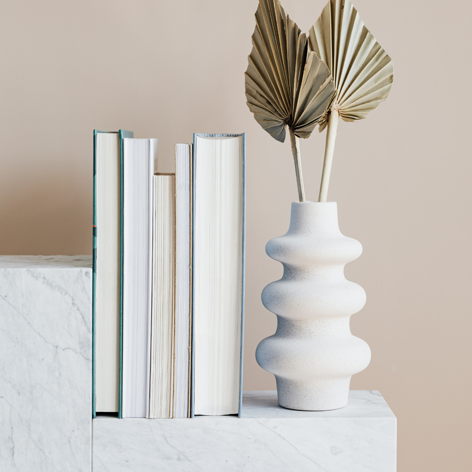 Decorative books and a vase on a marble surface.